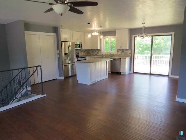 kitchen with stainless steel appliances, decorative backsplash, white cabinetry, and ceiling fan with notable chandelier