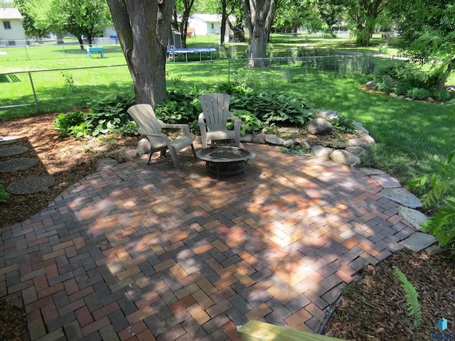view of patio / terrace featuring a fenced backyard, a trampoline, and an outdoor fire pit