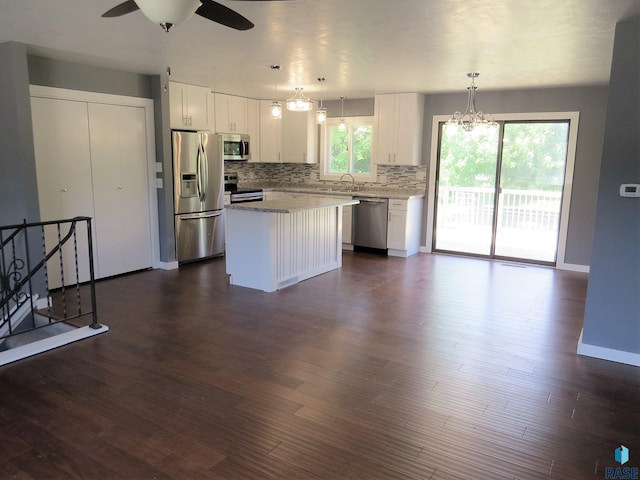 kitchen featuring a kitchen island, tasteful backsplash, a sink, stainless steel appliances, and white cabinetry