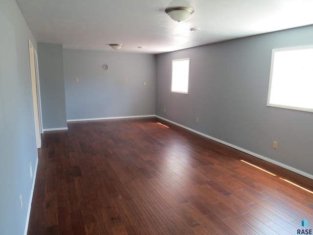 empty room featuring baseboards and dark wood-style floors