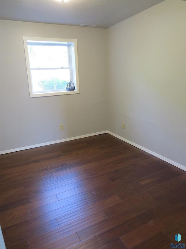 empty room with baseboards and dark wood finished floors
