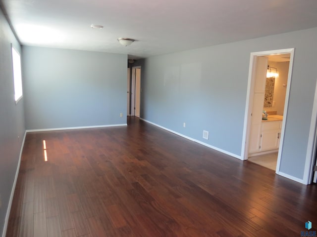 spare room with baseboards and dark wood finished floors