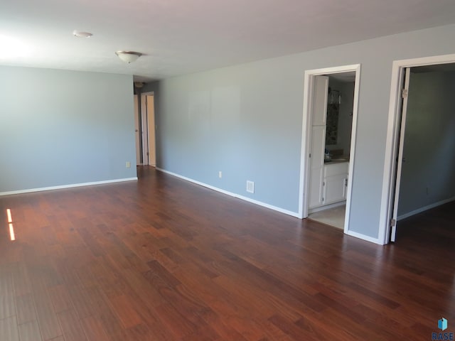 empty room with baseboards and dark wood-type flooring