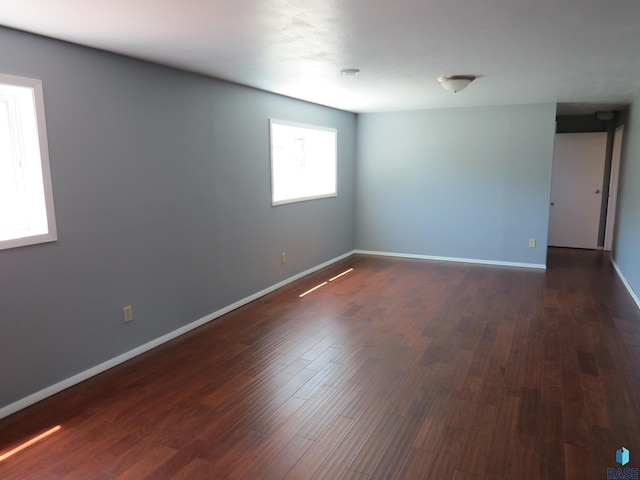 spare room with baseboards and dark wood finished floors