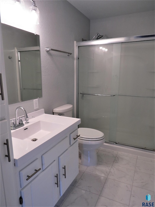 full bathroom featuring vanity, toilet, marble finish floor, and a stall shower