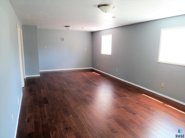 empty room featuring baseboards and dark wood-style floors