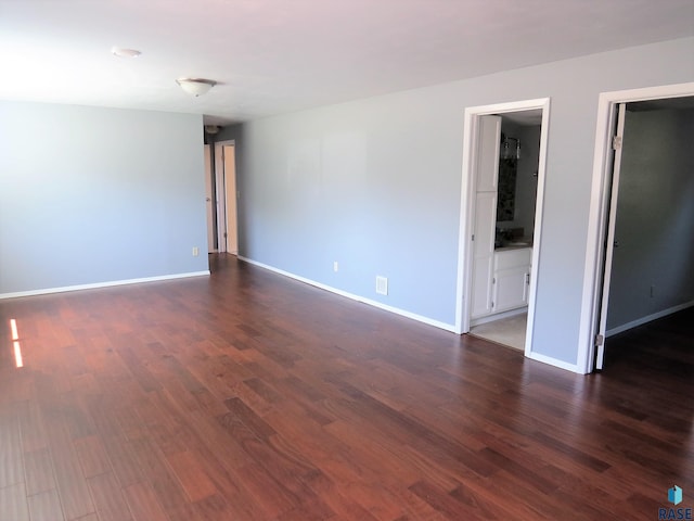 spare room featuring baseboards and dark wood-type flooring