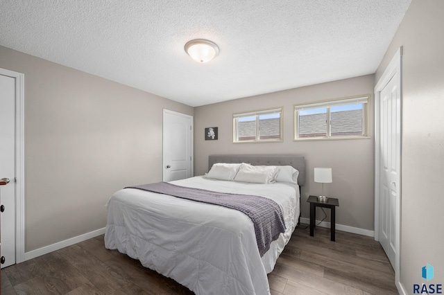 bedroom featuring a textured ceiling, baseboards, and wood finished floors