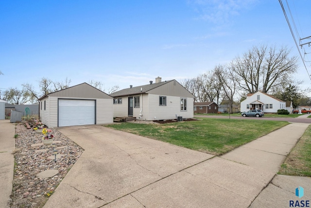 view of front of house featuring a garage, a front yard, a chimney, concrete driveway, and an outdoor structure
