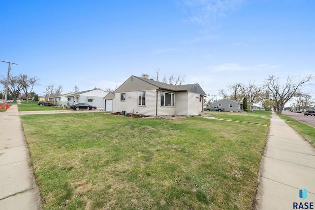 view of side of property featuring a lawn, a residential view, and a chimney