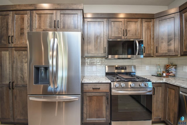 kitchen with stainless steel appliances, light stone counters, and decorative backsplash