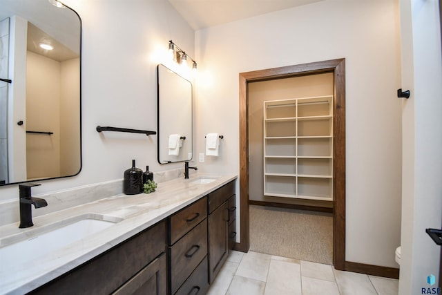 full bath with double vanity, toilet, a sink, and tile patterned flooring