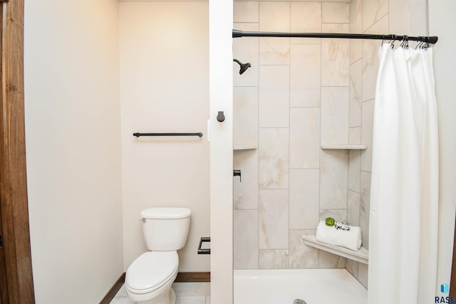 bathroom featuring toilet, baseboards, and a tile shower