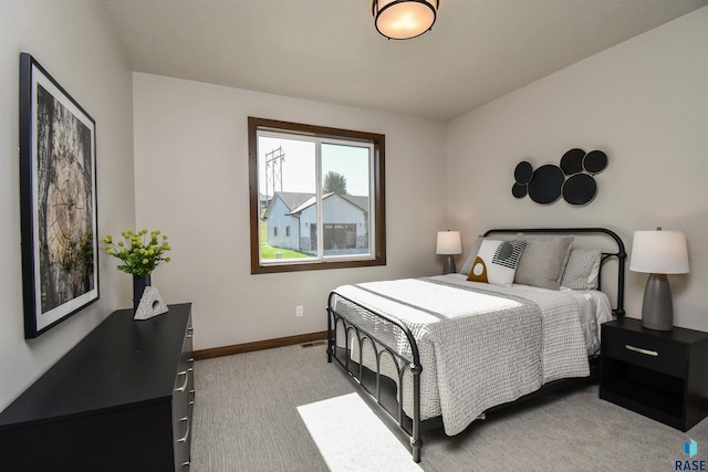bedroom with baseboards, visible vents, and light carpet