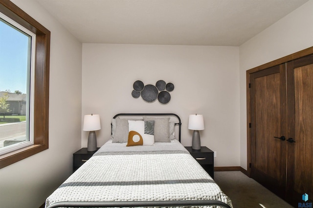 bedroom with baseboards, multiple windows, a closet, and dark colored carpet