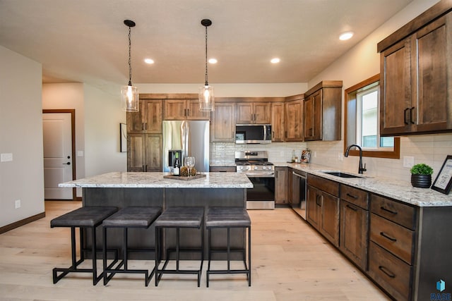 kitchen with a kitchen island, backsplash, appliances with stainless steel finishes, a sink, and a breakfast bar