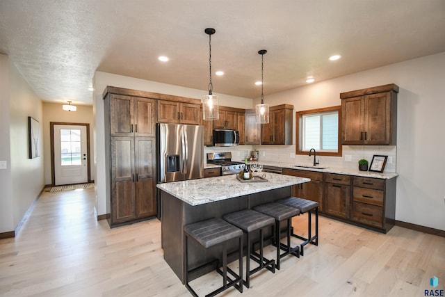 kitchen with a sink, light wood-style flooring, stainless steel appliances, a healthy amount of sunlight, and backsplash