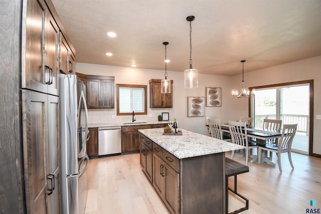 kitchen with backsplash, a center island, light wood finished floors, a breakfast bar, and stainless steel appliances