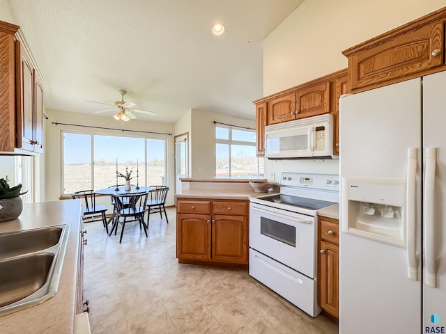 kitchen featuring a sink, white appliances, light countertops, brown cabinets, and a ceiling fan