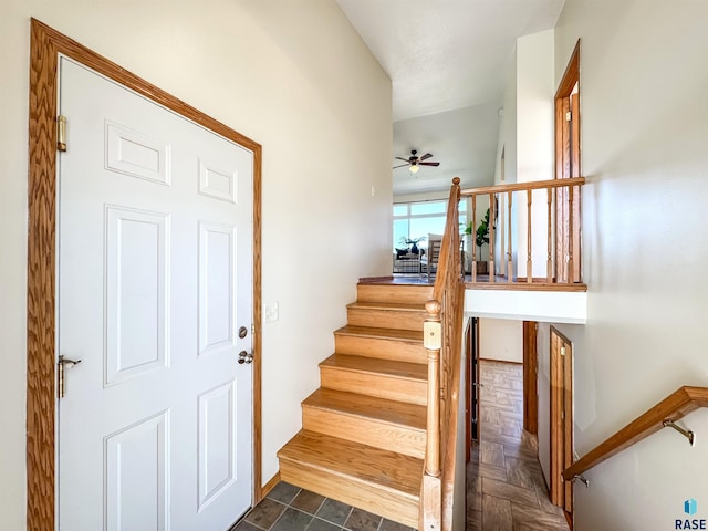 staircase featuring ceiling fan and baseboards