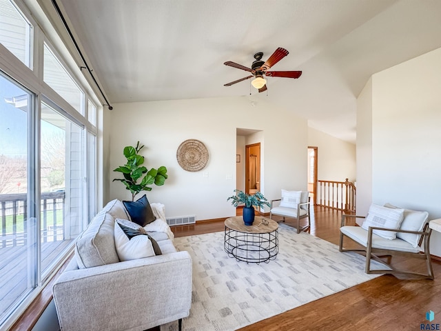living area featuring visible vents, lofted ceiling, wood finished floors, baseboards, and ceiling fan