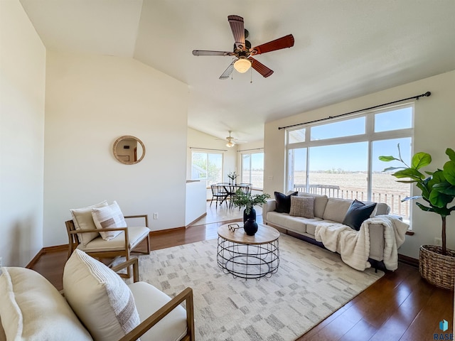living area featuring baseboards, ceiling fan, wood finished floors, and vaulted ceiling