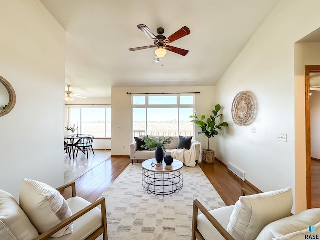 living area with a ceiling fan, wood finished floors, and a healthy amount of sunlight