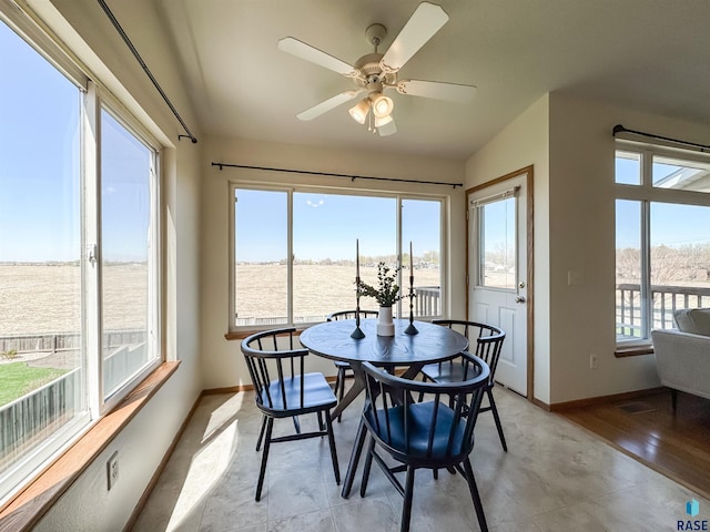 dining area featuring baseboards, ceiling fan, and a wealth of natural light