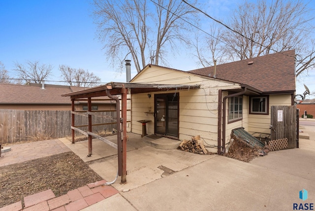 view of front of property with fence, a patio, and a shingled roof