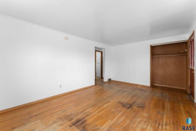 unfurnished bedroom with a closet, crown molding, and hardwood / wood-style flooring