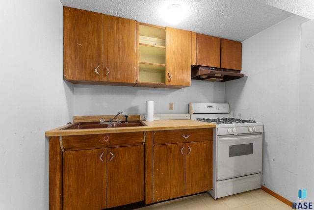 kitchen with a sink, brown cabinetry, gas range gas stove, and under cabinet range hood