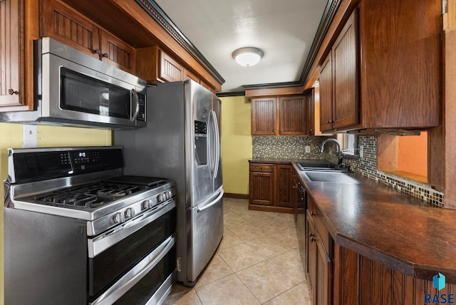 kitchen featuring decorative backsplash, appliances with stainless steel finishes, dark countertops, a sink, and light tile patterned flooring