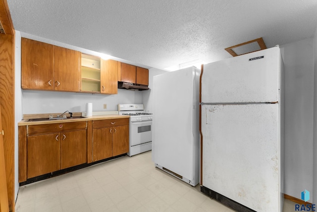 kitchen with a sink, white appliances, light countertops, light floors, and under cabinet range hood