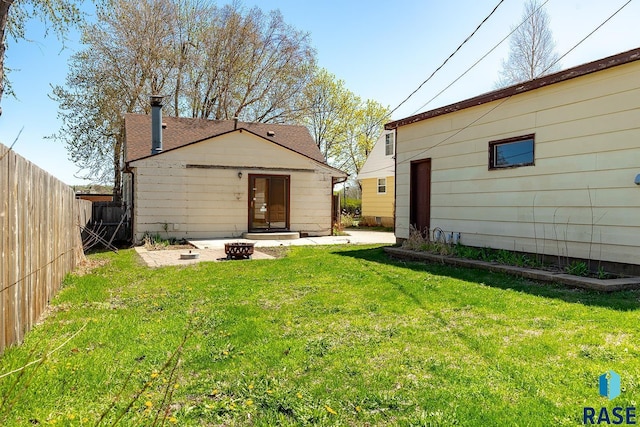 rear view of property featuring fence, a yard, and a fire pit