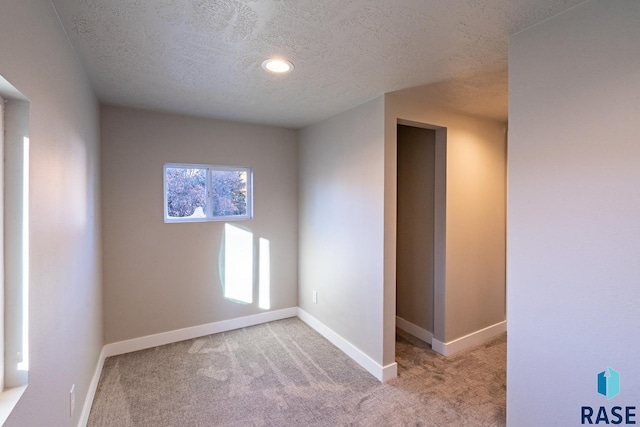 carpeted spare room featuring baseboards, recessed lighting, and a textured ceiling