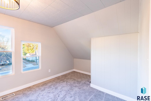 additional living space with baseboards, carpet, vaulted ceiling, and visible vents