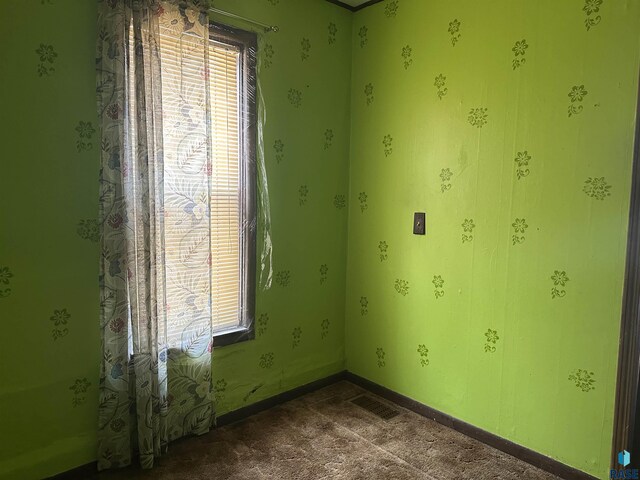 empty room featuring baseboards, dark carpet, and visible vents