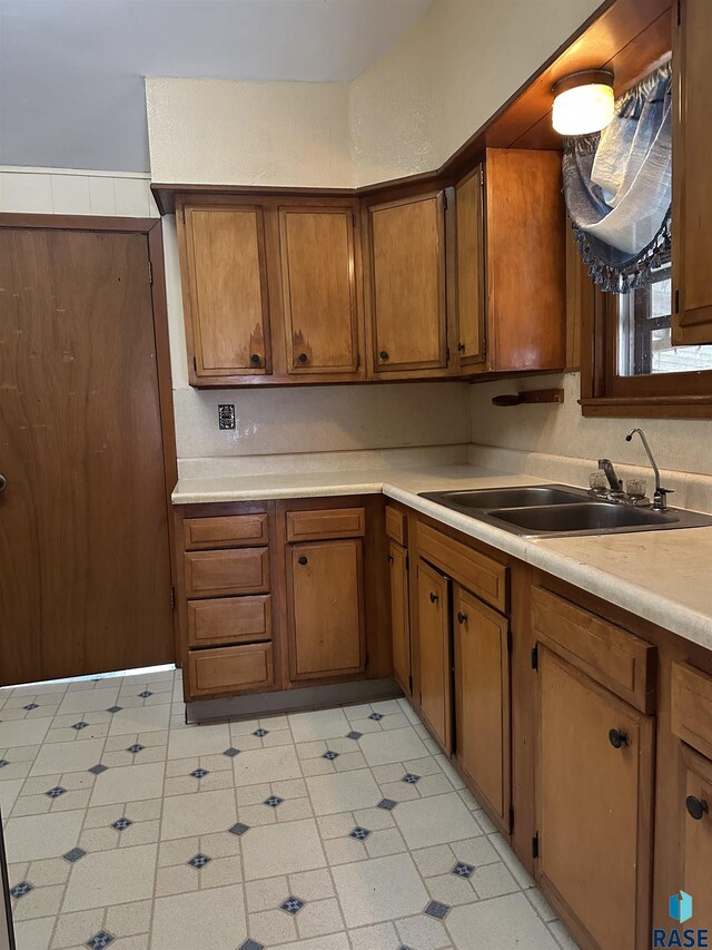 kitchen with brown cabinetry, a sink, and light countertops