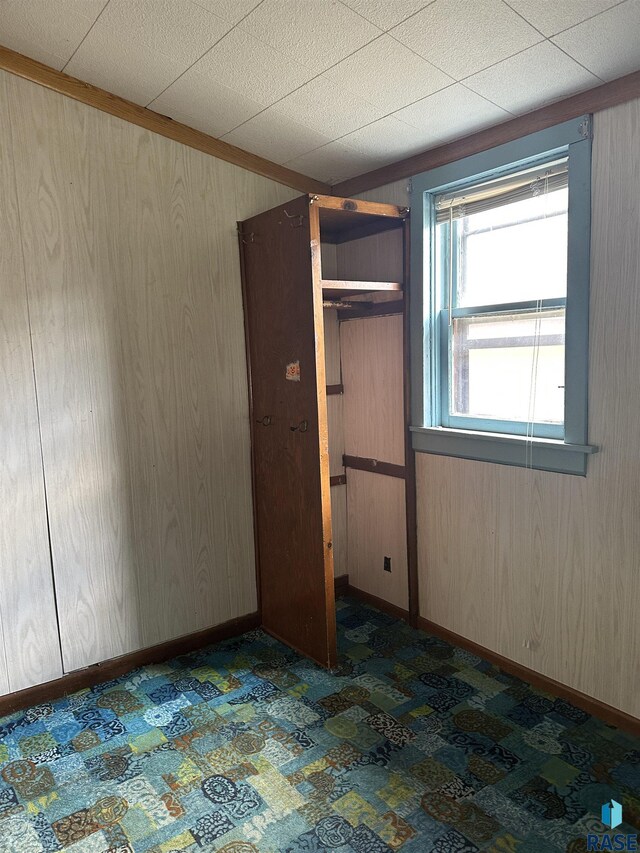 unfurnished bedroom featuring carpet flooring and wood walls