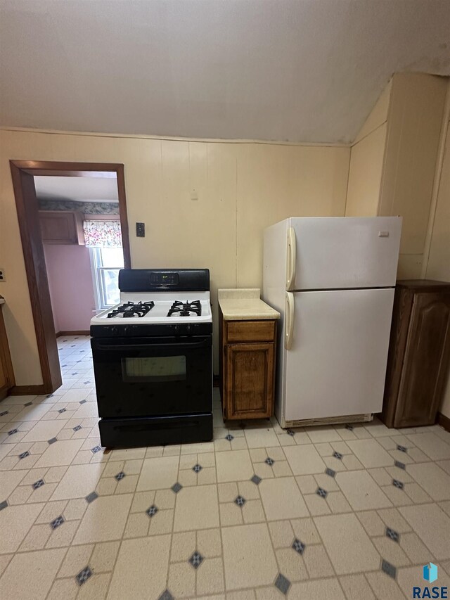 kitchen featuring freestanding refrigerator, light countertops, and gas range