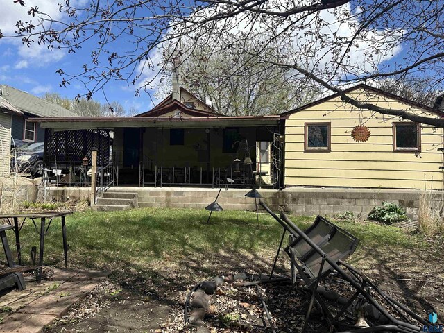 rear view of property featuring a yard and covered porch