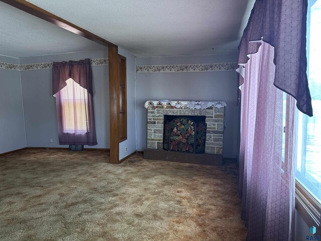 unfurnished living room with carpet floors, a textured ceiling, a healthy amount of sunlight, and a fireplace