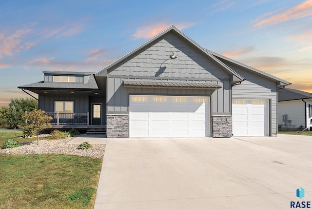 view of front of house with board and batten siding, driveway, stone siding, and a garage