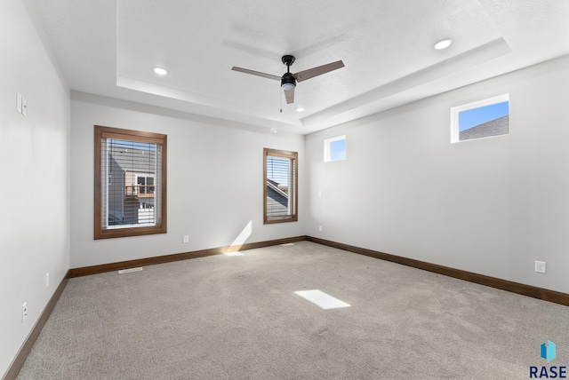 carpeted empty room featuring baseboards, a ceiling fan, a tray ceiling, and recessed lighting