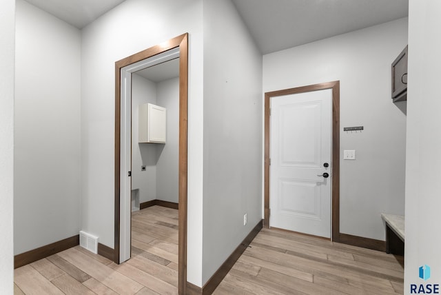 hallway with baseboards, visible vents, and light wood finished floors