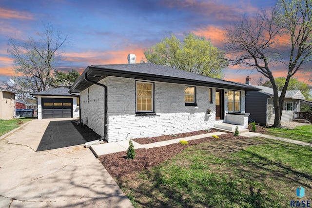 bungalow-style house with concrete driveway, brick siding, a chimney, and a detached garage