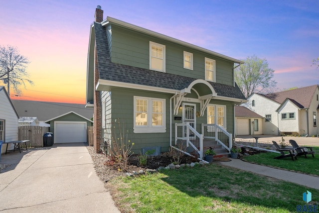 view of front of home with driveway, a chimney, an outbuilding, a garage, and a shingled roof
