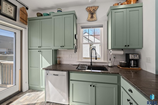 kitchen with backsplash, green cabinetry, a sink, and dishwasher