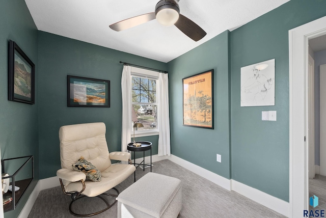 living area featuring carpet floors, a ceiling fan, and baseboards