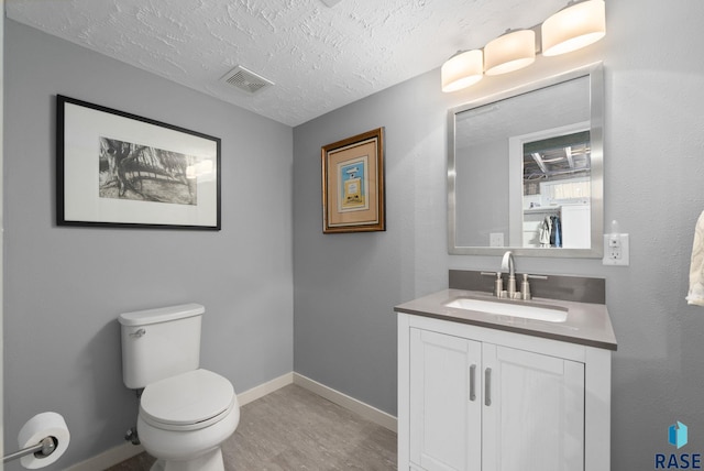 bathroom featuring visible vents, baseboards, wood finished floors, and vanity